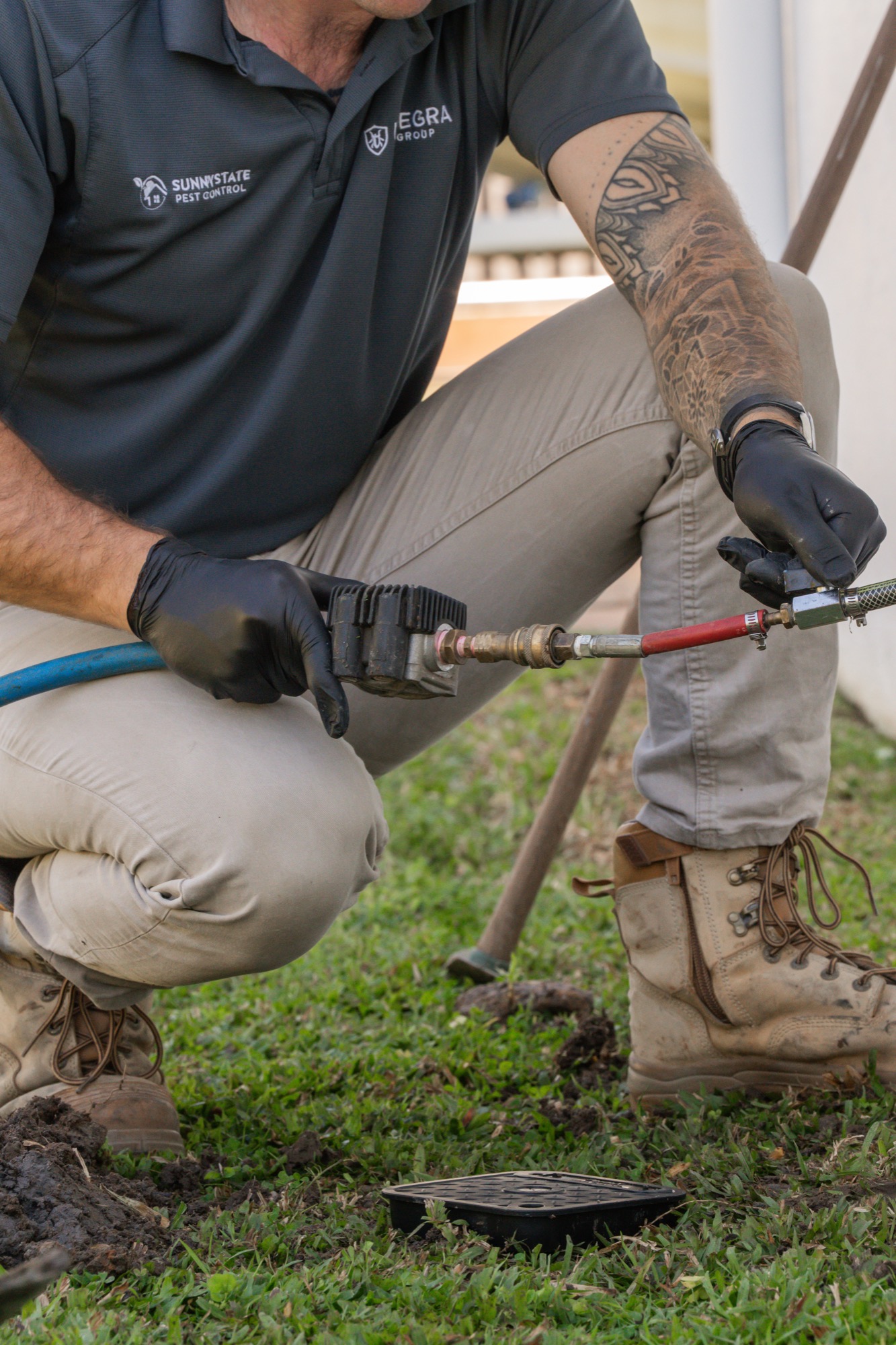 Technician connecting hose fittings to reticulation system during termite barrier top up