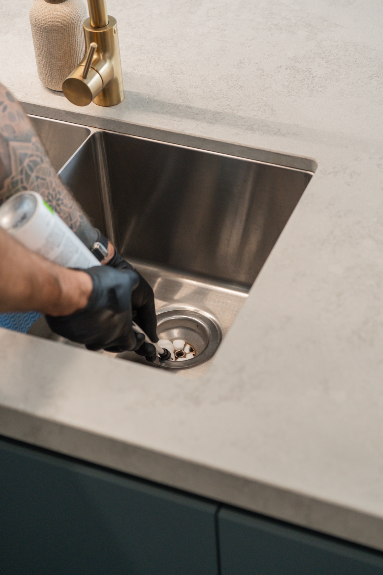 Sunnystate technician applying cockroach gel bait at kitchen sink drain